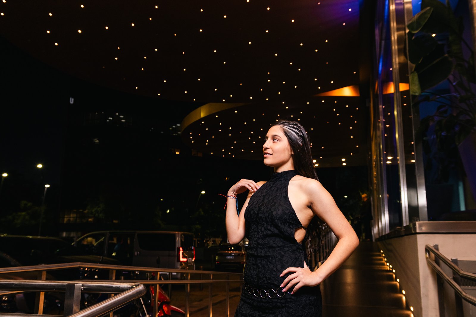 Brunella con vestido negro bajo un cielo de luces.
